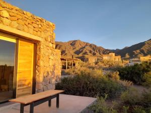 盧漢德庫約的住宿－Bendita Piedra Suites, Las Compuertas Lujan de Cuyo，坐在沙漠中建筑物外的长凳