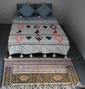 uma cama com uma colcha em cima de um tapete em ASARAG em Mirleft