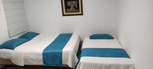 2 Betten in einem weißen Zimmer mit blauen Kissen in der Unterkunft Hotel Mykonos Manta in Manta