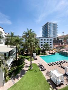 - une vue sur la piscine bordée de palmiers et de bâtiments dans l'établissement Hotel Gran Plaza & Convention Center, à Guanajuato