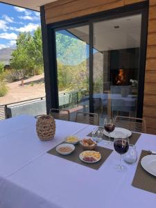 a white table with food and wine glasses on it at Cabaña de alta categoría en Vistacalma, Potrerillos in Guido