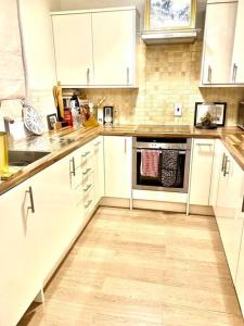 a kitchen with white cabinets and a wooden floor at Chic studio in Leicester Sqaure! in London