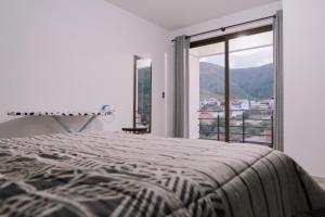 a white bedroom with a bed and a large window at Aires de Altura y Singani in Tarija