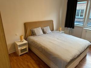 een slaapkamer met een bed met een nachtkastje en een raam bij Appartement rénové in Brussel