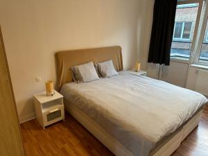 a bedroom with a bed with a night stand and a window at Appartement rénové in Brussels