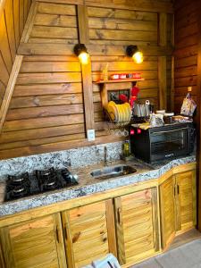 a kitchen with a stove and a sink in a cabin at Chalé de Madeira em Vargem Alta in Vargem Alta