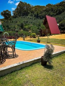 a swimming pool with a table and a bench and a house at Chalé de Madeira em Vargem Alta in Vargem Alta