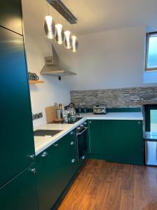a kitchen with green cabinets and wooden floors at Bill's Barns Apartment 2 in Kenmare