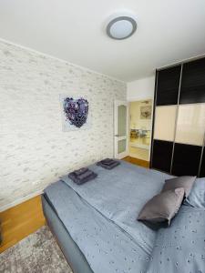 ein Schlafzimmer mit einem blauen Bett und einer Wand in der Unterkunft Marina Bay Apartman in Budapest