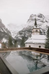 a view of a church with a snow covered mountain at Hotel Fiescherblick in Grindelwald