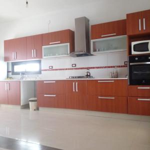 a large kitchen with brown cabinets and a microwave at Casa en Chilecito equipada cerca ruta 40 in Chilecito