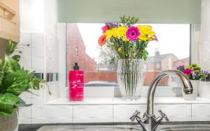 un jarrón de flores sentado en un mostrador junto a una ventana en Entire House in Ipswich, en Ipswich 19 fotos más