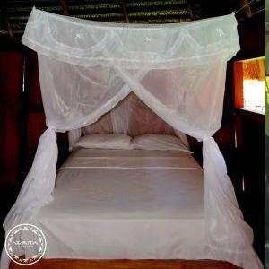 a bed with a mosquito net on top of it at Waita Lodge in Cuyavenus