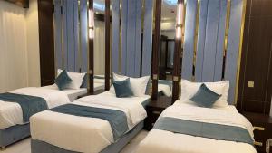 a room with three beds and a mirror at الجوهرة سويت للشقق المخدومة in Shahār