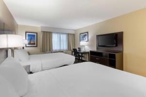 a hotel room with two beds and a flat screen tv at Best Western St. Louis Inn in Arnold