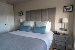 um quarto com uma cama grande e 2 almofadas azuis em Oatlands Park Hotel em Weybridge