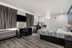 a bedroom with a bed and a desk and a television at Studio 6 Suites Perris, CA in Perris