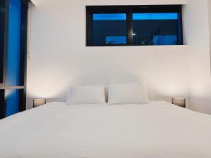 a bedroom with a white bed with a window at Art House with 2 Kingbeds at Cultural Centre in Brisbane