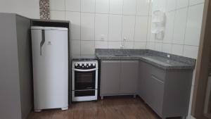 a small kitchen with a refrigerator and a stove at Recanto da Lagoa in Passo de Torres +14 photos