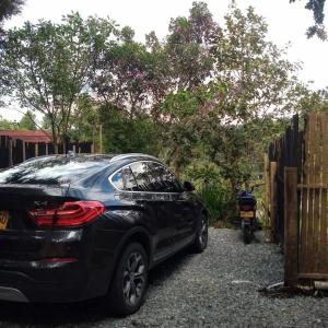 Ein schwarzes Auto, das in einer Einfahrt neben einem Zaun parkt. in der Unterkunft Hermosa cabaña con huerta - Casa verde in Medellín