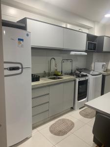 eine Küche mit weißen Geräten und einem weißen Kühlschrank in der Unterkunft Resort em Barra velha, pé na areia e vista mar in Barra Velha