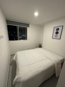 een slaapkamer met een wit bed en een raam bij Apartamento en el poblado vista a todo Medellín. in Medellín