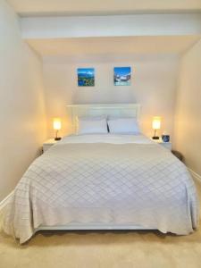 een slaapkamer met een wit bed met twee foto's aan de muur bij Cozy 2BR Midpoint to Seattle, Mt.Rainer & Tacoma in Auburn