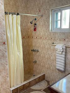 een douche met een douchegordijn in de badkamer bij Veronica Homestay Lucea Jamaica in Lucea
