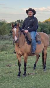 un hombre está sentado sobre un caballo en un campo en Cabaña en el campo, en Tacuarembó