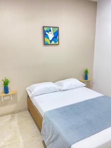 a bedroom with a bed and a painting on the wall at Guakmaya hostel in Cartagena de Indias