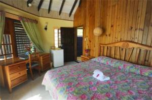 a bedroom with a bed with a dresser and a desk at Xtabi Resort in Negril