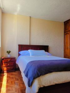 a bedroom with a large bed with a blue blanket at Casa Cuscungo Family Experience in Quito