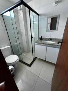 a bathroom with a toilet and a glass shower at Apt. em Praia do Sul de Ilhéus in Ilhéus