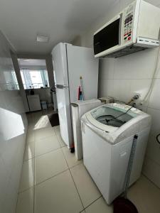 a small kitchen with a refrigerator and a microwave at Apt. em Praia do Sul de Ilhéus in Ilhéus