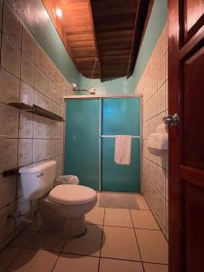 a bathroom with a toilet and a glass shower at Pura Natura Lodge Manuel Antonio in Manuel Antonio