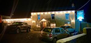 dois carros estacionados em frente a um edifício à noite em The Butchers Arms - Grill Pub and Accommodation em Merthyr Tydfil