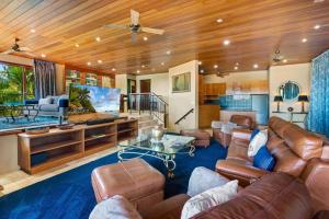 Barong Luxury Home overlooking Cairns Unrivalled privacy and location في كيرنز: غرفة معيشة مع أثاث جلدي ومروحة سقف
