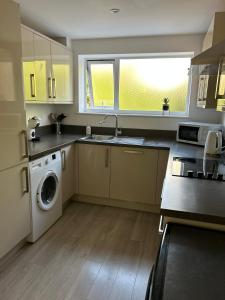 a kitchen with a sink and a washing machine at Wembley Accommodation in London