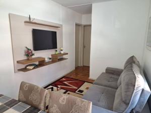 uma sala de estar com um sofá e uma televisão de ecrã plano em Charmoso apartamento próximo ao Consulado EUA em Porto Alegre