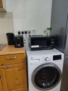 a kitchen with a washing machine and a microwave at 1 bedroom flat in Neepsend