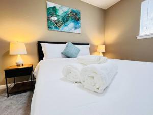 Un dormitorio con una cama blanca con toallas. en Monumental Stay Near DC‘s Best!, en Temple Hills
