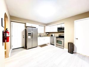 una cocina con electrodomésticos de acero inoxidable y armarios blancos en Monumental Stay Near DC‘s Best! en Temple Hills