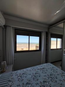 a bedroom with a bed and a view of the beach at Apto 2 dorm com vista para o mar in Capão da Canoa