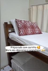 uma cama com uma almofada vermelha e branca em Hostel Casa Uniao em Maracaju