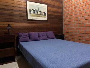 1 dormitorio con cama y pared de ladrillo en Casa Guarda do Embaú, en Guarda do Embaú