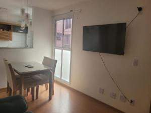 ein Esszimmer mit einem Tisch und einem TV an der Wand in der Unterkunft Residencial Jardim da costa in João Pessoa