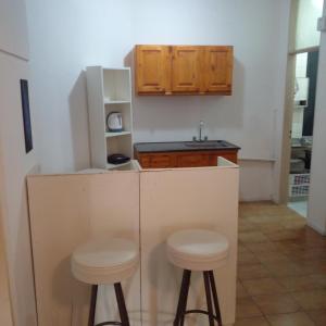 a small kitchen with two stools and a refrigerator at Amplio departamento zona centro in Paraná