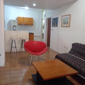 a living room with a red chair and a kitchen at Amplio departamento zona centro in Paraná