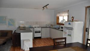 een keuken met een witte koelkast en een tafel bij Melina's Cottage Is A Neat, Tidy, Budget Property in Coffin Bay