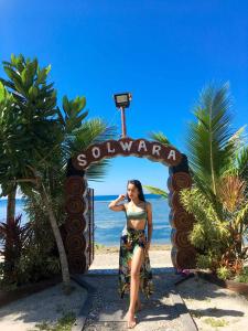 Una donna seduta davanti a un cartello sulla spiaggia di Solwara Beach Resort a Balete